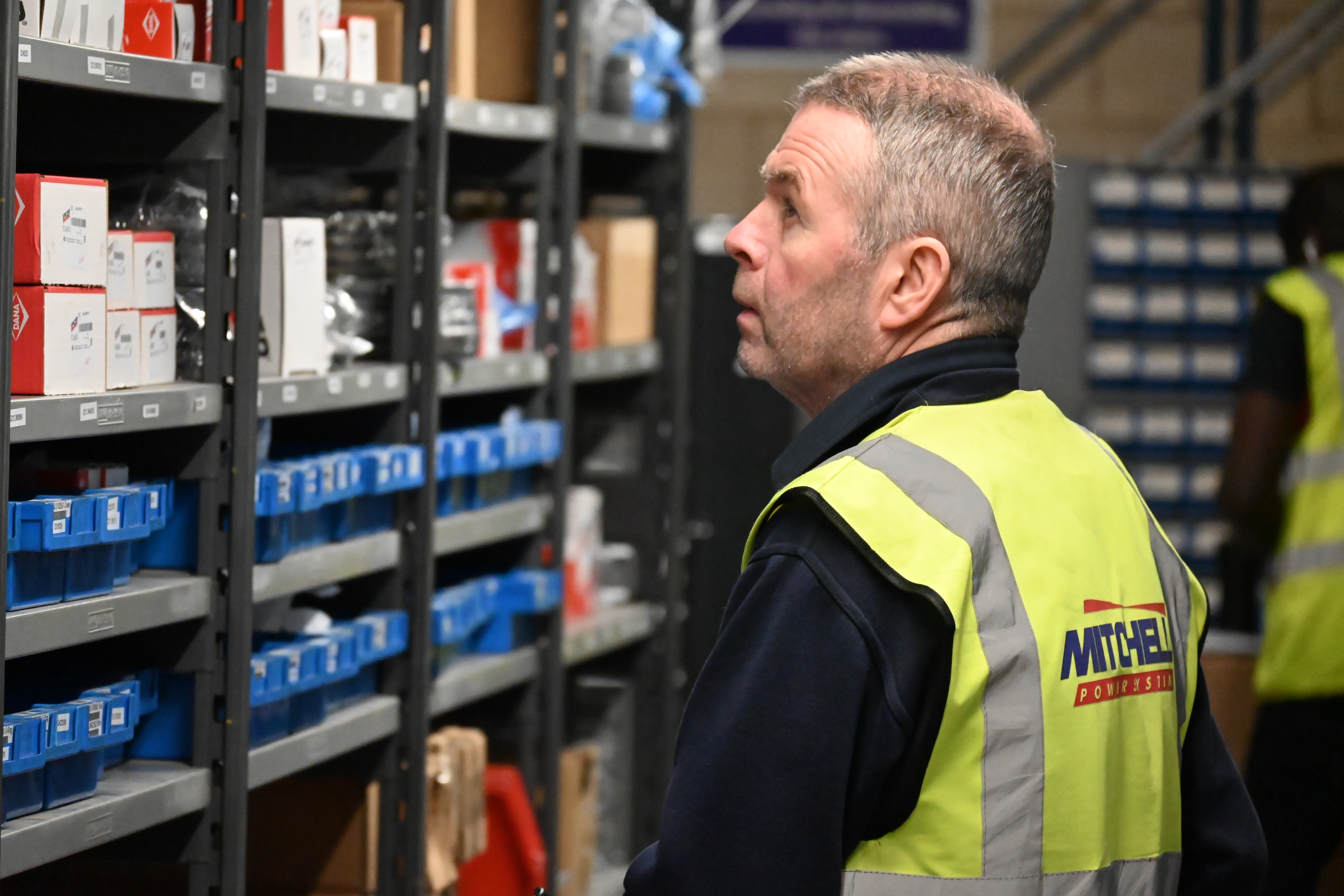 warehouse worker looking for products on shelf in high vis